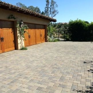 Cobblestone driveway leading up to a Spanish style home