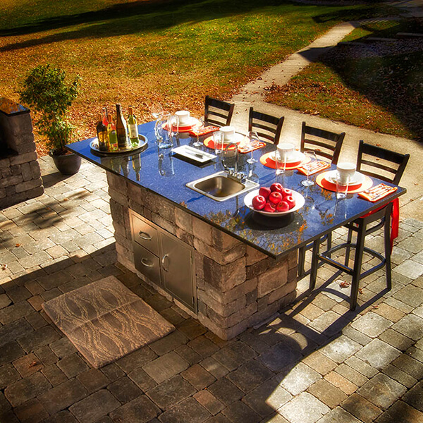 outdoor dining table with four chairs and food and drinks linking the table on a paver patio